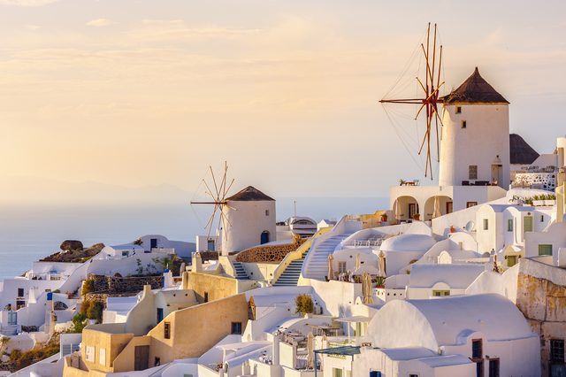 Santorini'de gün batımı ışığında Oia'nın beyaz evleri ve yel değirmenleri