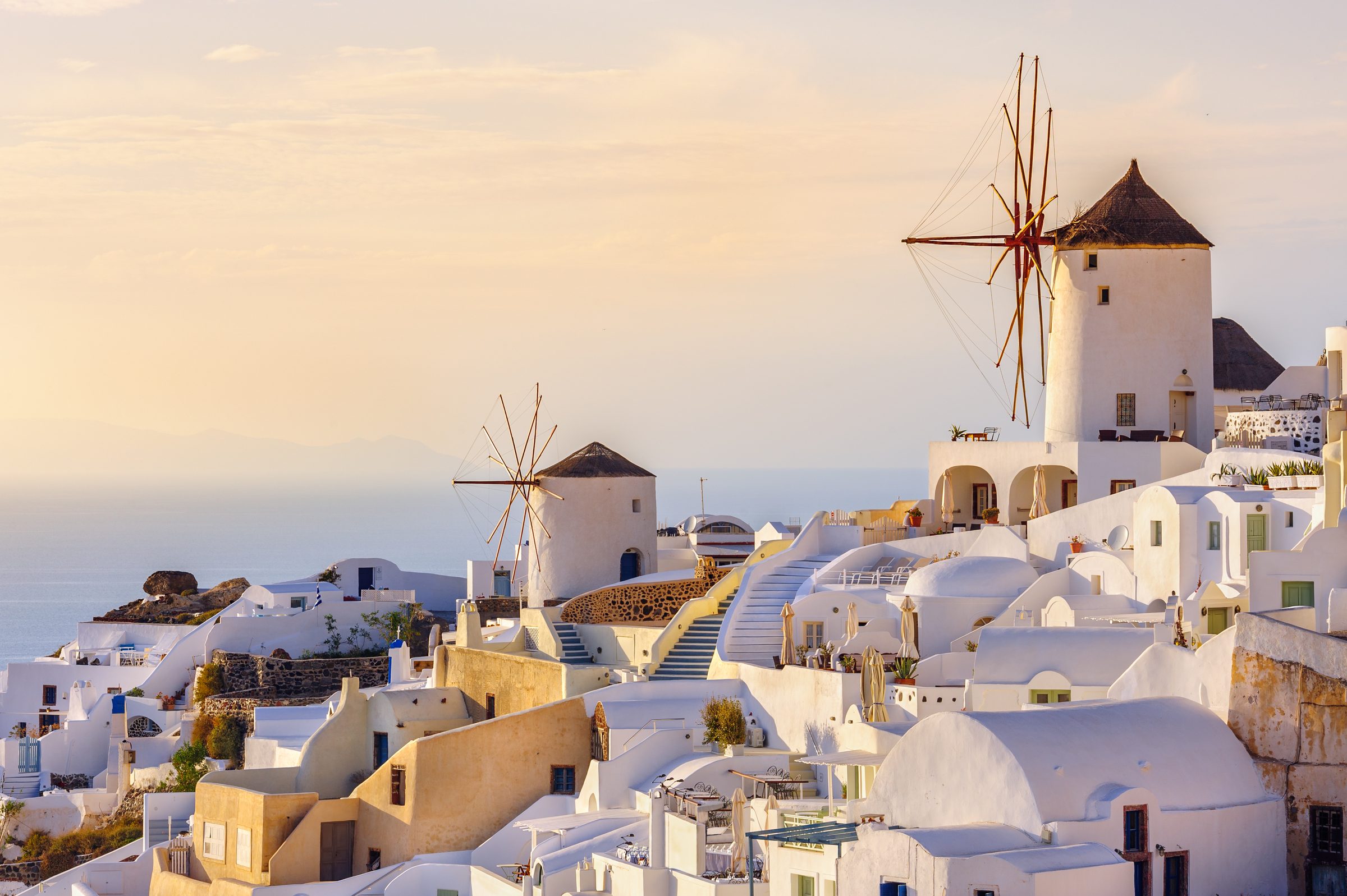 Santorini'de gün batımı ışığında Oia'nın beyaz evleri ve yel değirmenleri